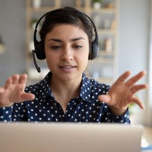 Person wearing headphones with hands up at computer screen